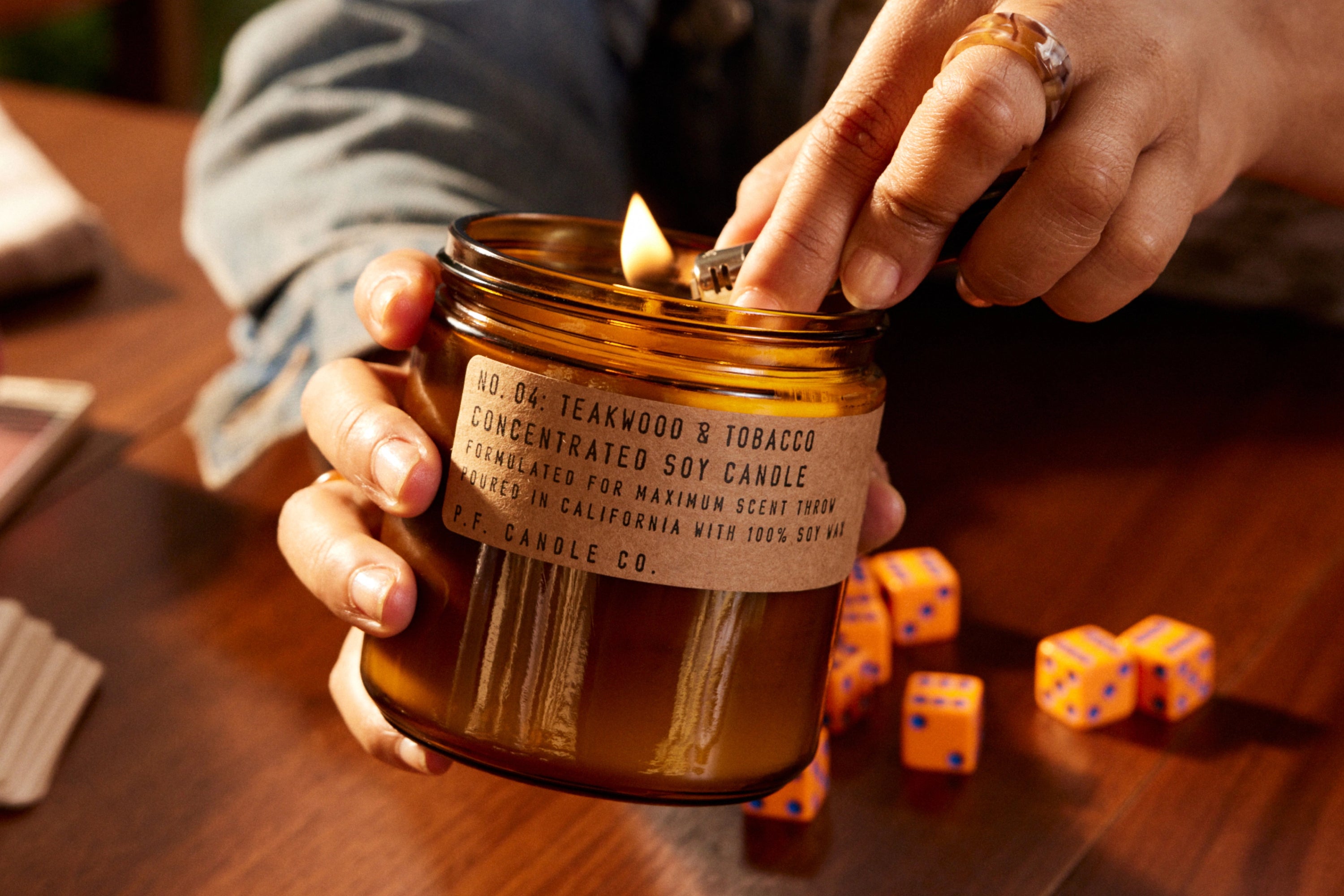 Teakwood & Tobacco Concentrated soy candle being lit up using a ligher.