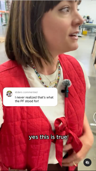 A woman in a red vest and necklace poses confidently, showcasing her stylish outfit.