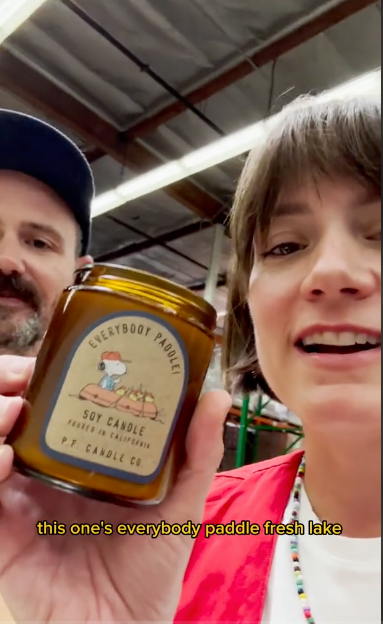 A couple holds a jar of Soy Candle, smiling at the camera, emphasizing their connection and appreciation for the product.